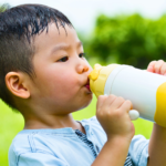 asian child drinking water in park