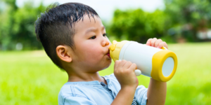 asian child drinking water in park