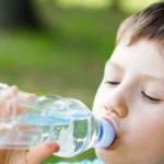 boy drinking water from plastic bottle