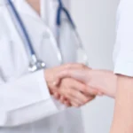 doctor with stethoscope shaking hand with woman patient
