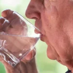 old man drinking a glass of water