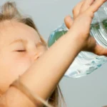 girl drinking water from plastic bottle