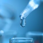 Water hardness testing. Dropper with a water drop over test tubes.