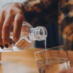 Pouring drinking water from a bottle into a glass. Ensure water safety in homes with old lead solder.