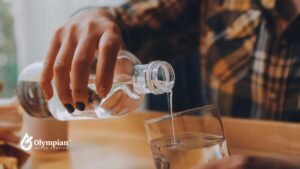 Pouring drinking water from a bottle into a glass. Ensure water safety in homes with old lead solder.