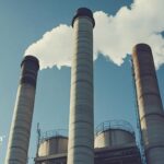 Industrial smokestacks release emissions into the sky. Concerned about PFAS regulations and drinking water safety.