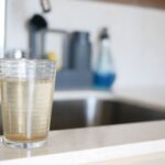 Rusty water in a glass. Understanding causes of discolored tap water in your home.