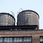 Two wooden water towers on a building rooftop. Purpose of water towers for water storage and pressure.