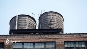 Two wooden water towers on a building rooftop. Purpose of water towers for water storage and pressure.