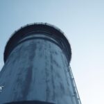 Rooftop water tower against a blue sky. Water tower maintenance and inspection information.