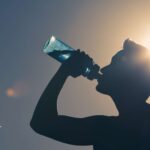 Silhouette of person drinking water from a bottle. Water quality and safety are important.