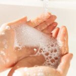 Soft water feeling. Hands with soap under running water. Softened water creates a slippery sensation.
