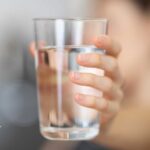 Hand holding a glass of water. Concerns about chlorine exposure from drinking water.
