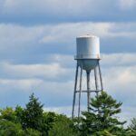 Tall water tower against a cloudy sky. Water towers ensure consistent water pressure in tall buildings.