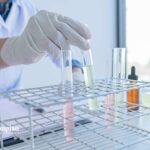 Scientist in lab coat analyzing water samples in test tubes. Water testing for purity and safety.