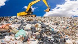 Excavator on landfill. Mercury (Hg) pollution from waste impacts water quality.