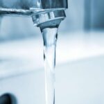 Faucet running with clear water. Understanding PFAS in NYC drinking water quality and potential contamination.