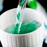 Green mouthwash being poured into a cup. Fluoride dental hygiene concept.