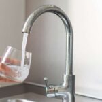 NYC tap water: Glass being filled with water from a faucet. Fluoride in tap water concept.