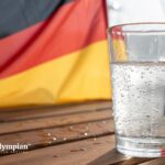 Is Germany tap water drinkable? Glass of water with bubbles and German flag. Safe drinking water concept.