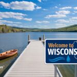 Scenic Wisconsin lake view with dock, boat, and Welcome to Wisconsin sign. Safe tap water concept.