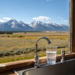 Wyoming tap water. Glass filling with water from faucet, mountain view. Water quality testing.