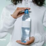Bottled water held by a person. Concerns about PFAS forever chemicals in bottled water.