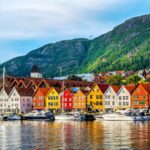 Bergen, Norway, water quality. Colorful buildings line the harbor with boats, mountains in the background.