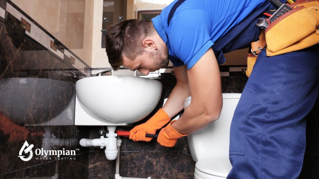 Plumber fixing sink plumbing. Hydrogen sulfide in well water can corrode pipes. Get water testing to prevent damage.