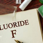 Fluoride in Well Water. Beaker, test tubes, and pen on open book. Water testing for fluoride levels.