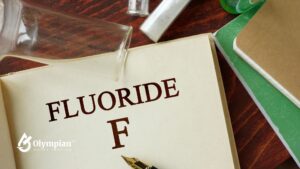 Fluoride in Well Water. Beaker, test tubes, and pen on open book. Water testing for fluoride levels.