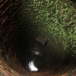 Deep well with brick, moss, and water. Well water pre-filtration prevents problems.