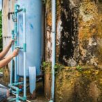 Well water filter maintenance. Technician inspecting water filtration system for contaminated well. Carbon filter maintenance.