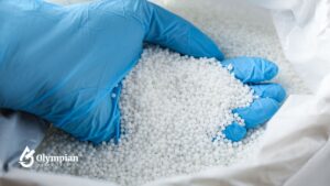 Nitrates in well water. Hand in blue glove holding white nitrate pellets for water testing.
