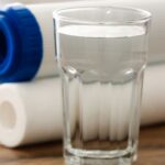 Water filters and a glass of water. Carbon filters alone aren't enough for contaminated wells. Water purification concept.