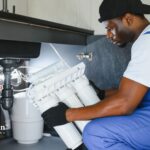 Reverse osmosis well water system install. Technician installs water filter. Well water purification.