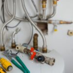 Plumbing materials and tools on a water heater. Well water safety and plumbing considerations.