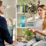 Woman in therapy session. Mental health support after Flint water crisis. Counselor listens, taking notes.