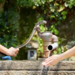 Couple using well water pump. Get your well water tested regularly for water quality and safety.