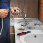 Replacing Fixtures: Plumber with new faucet and plumbing parts. Home well water fixture replacement.